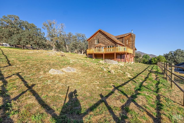 back of property with a lawn, a rural view, and a wooden deck