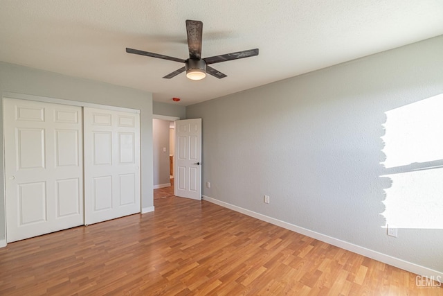 unfurnished bedroom with wood-type flooring, a textured ceiling, a closet, and ceiling fan