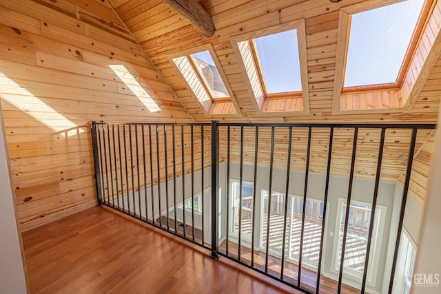 hall featuring hardwood / wood-style floors, wood walls, vaulted ceiling with skylight, and wooden ceiling