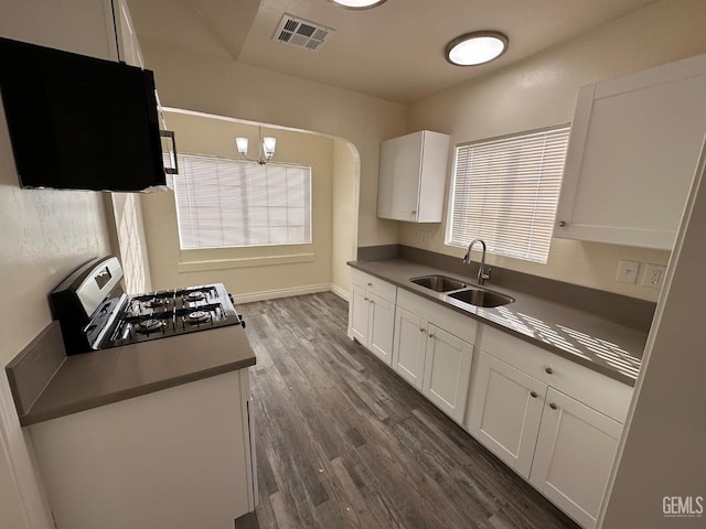 kitchen with a sink, visible vents, white cabinetry, range, and dark countertops