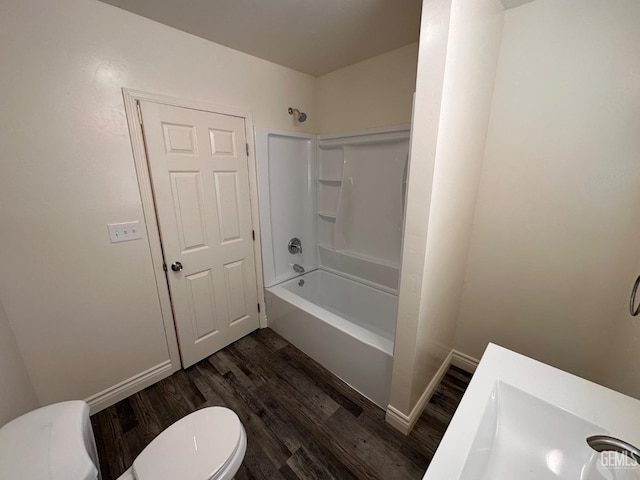 full bathroom with bathing tub / shower combination, toilet, a sink, wood finished floors, and baseboards