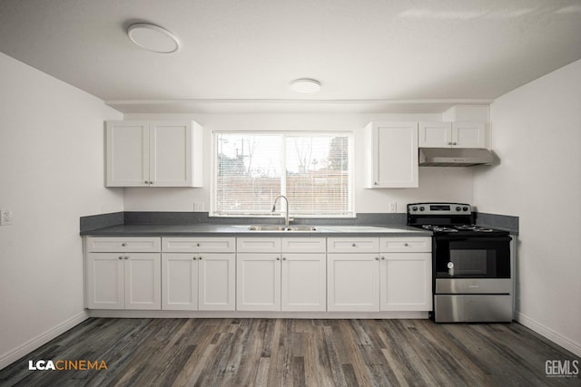 kitchen with dark countertops, stainless steel electric range, under cabinet range hood, white cabinetry, and a sink