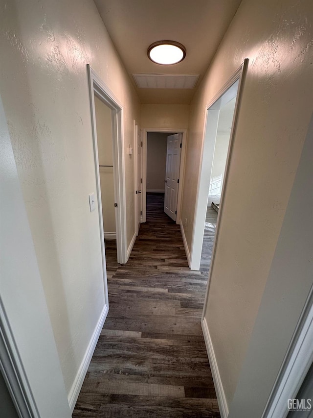 corridor with dark wood-type flooring and baseboards