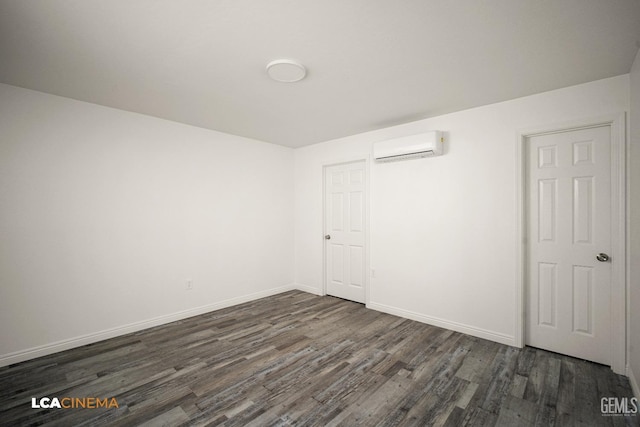 unfurnished bedroom featuring dark wood-style floors, baseboards, and an AC wall unit