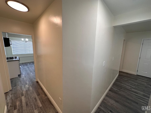 hallway with dark wood-type flooring and baseboards