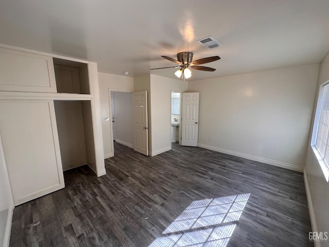 unfurnished bedroom featuring dark wood-style flooring, a closet, visible vents, and baseboards