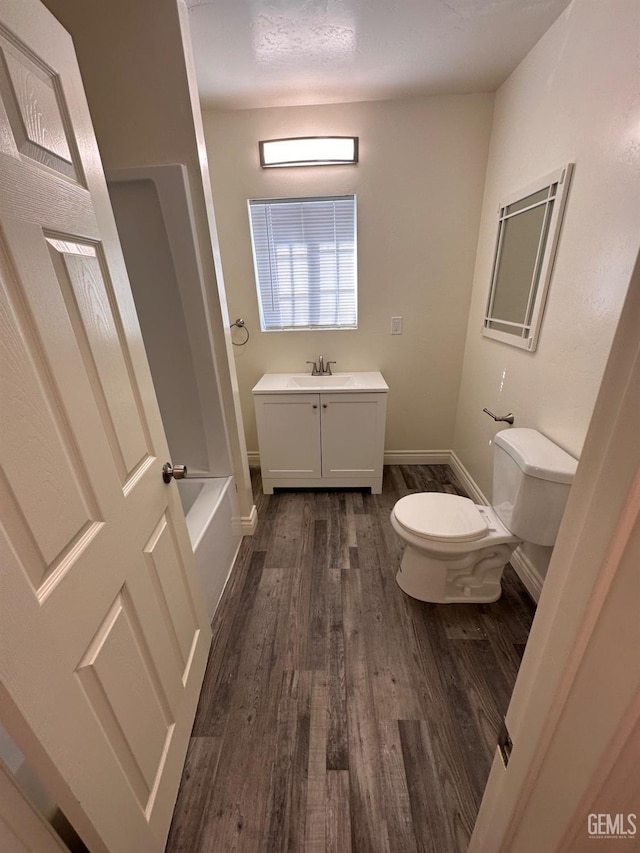 full bath with toilet, vanity, wood finished floors, baseboards, and walk in shower