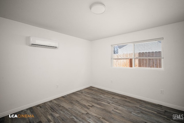 spare room with a wall unit AC, dark wood finished floors, and baseboards