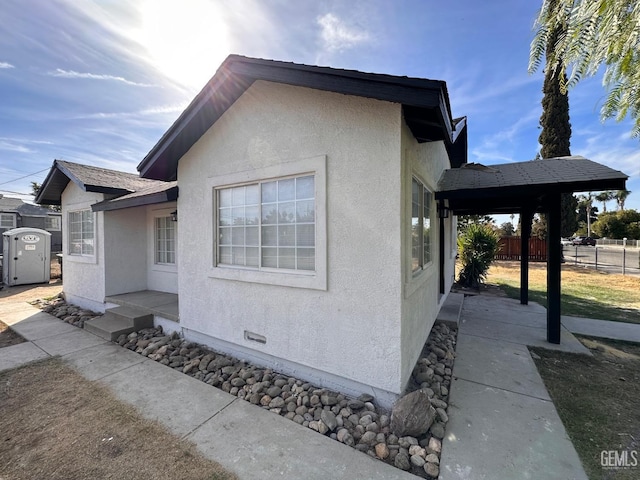 view of side of property with fence and stucco siding