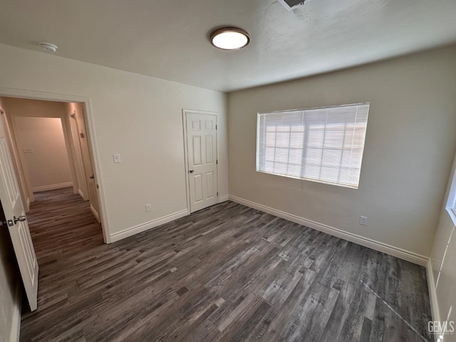 unfurnished bedroom with dark wood-type flooring and baseboards