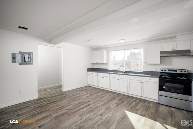 kitchen featuring dark countertops, stainless steel range with electric cooktop, under cabinet range hood, and white cabinetry