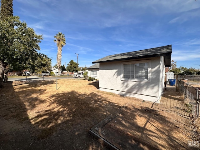 view of side of property with fence and stucco siding