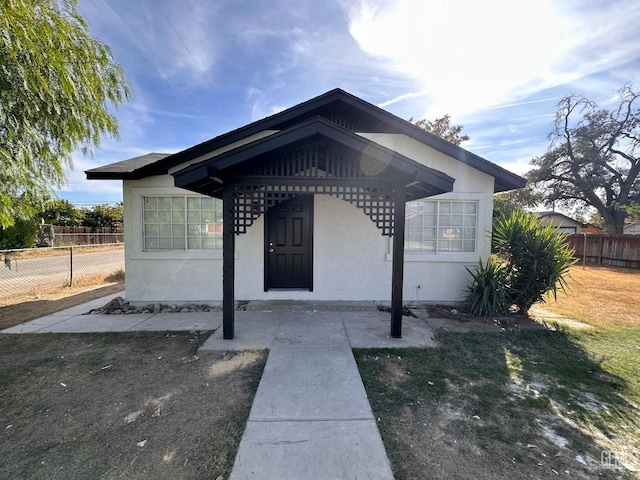 view of exterior entry featuring fence and stucco siding