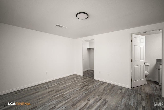 unfurnished bedroom with dark wood-style flooring, visible vents, and baseboards