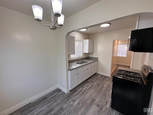 kitchen with dark wood-style floors, white cabinetry, a sink, and gas range