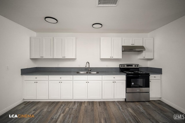 kitchen with dark countertops, under cabinet range hood, electric range, and white cabinets