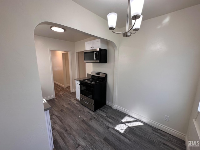 kitchen featuring arched walkways, decorative light fixtures, dark wood finished floors, stainless steel appliances, and white cabinets