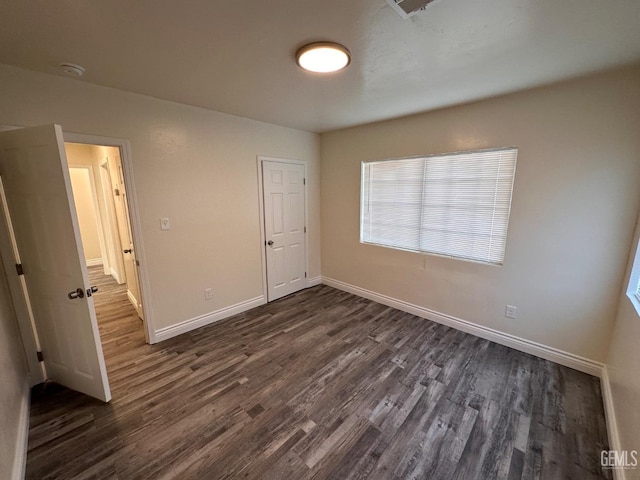 unfurnished bedroom featuring dark wood-style flooring and baseboards