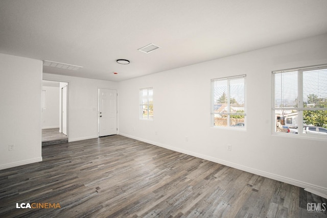 unfurnished room with visible vents, baseboards, and dark wood-style flooring