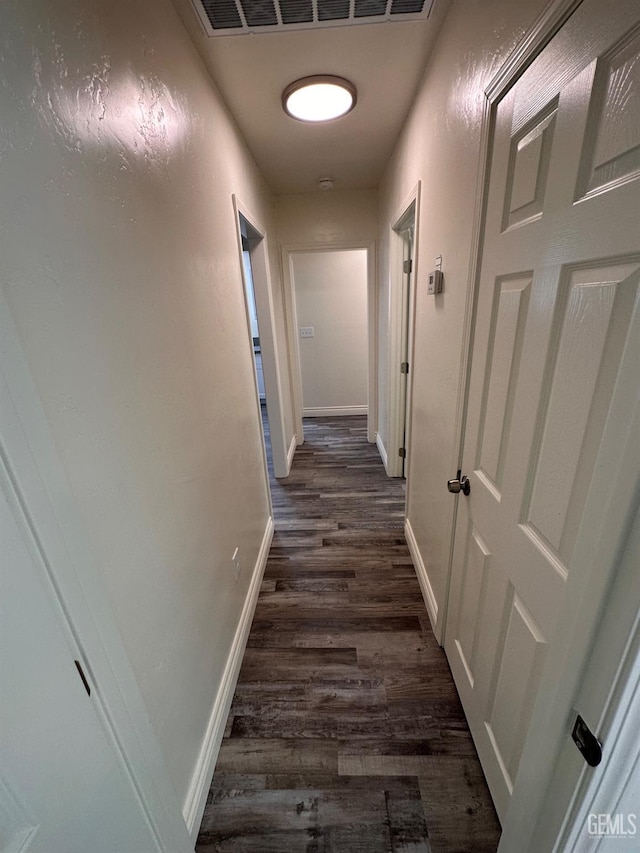 hallway featuring dark wood-style flooring and baseboards