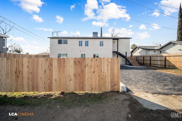 exterior space featuring stairs, fence, and stucco siding