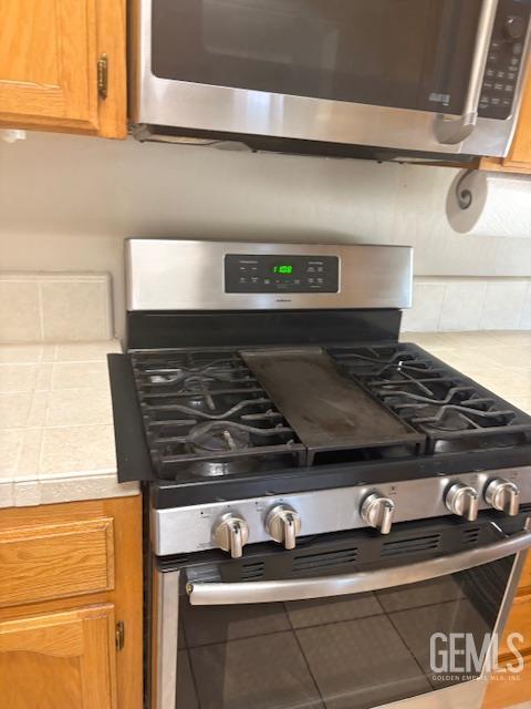 12006 Roaring River Ave, Bakersfield, CA 93311 - kitchen view of appliances with stainless steel finishes, light countertops, brown cabinets, and decorative backsplash