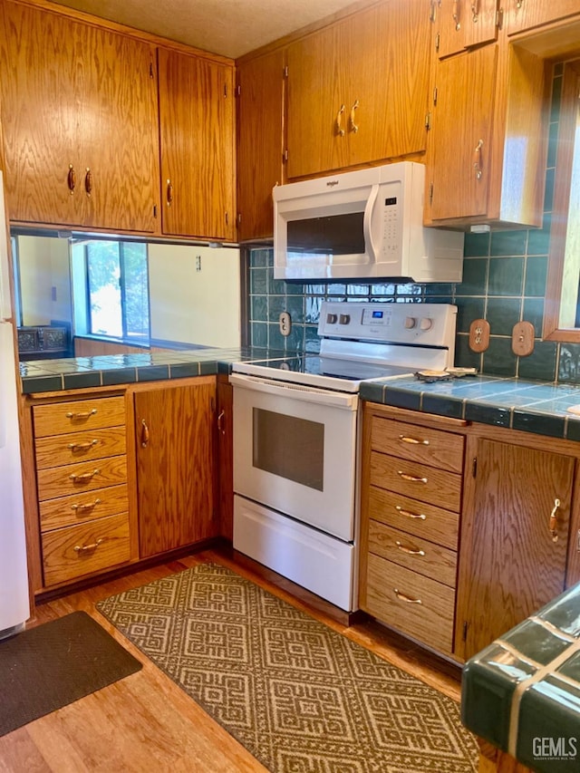 45842 Park Dr, Posey, CA 93260 - kitchen with wood finished floors, brown cabinets, tile counters, white appliances, and decorative backsplash