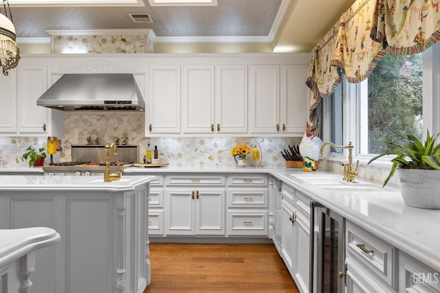 701 Oleander Ave, Bakersfield, CA 93304 - kitchen with wine cooler, a sink, wall chimney range hood, visible vents, and light wood-style floors