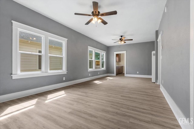 spare room with wood finished floors, a ceiling fan, and baseboards