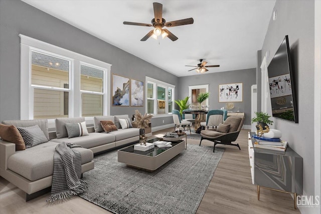 living room featuring wood finished floors, baseboards, and ceiling fan