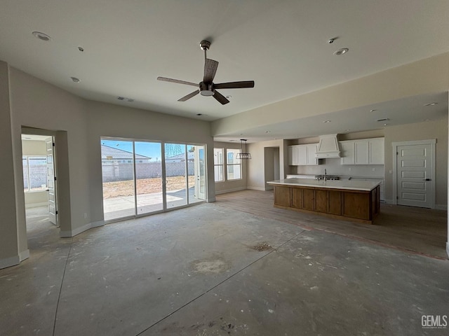 unfurnished living room with unfinished concrete flooring, a sink, visible vents, and baseboards