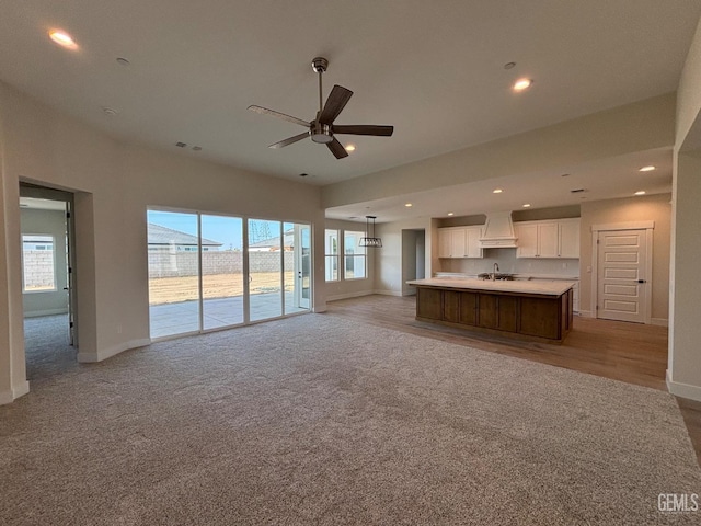 unfurnished living room with recessed lighting, baseboards, light carpet, and ceiling fan