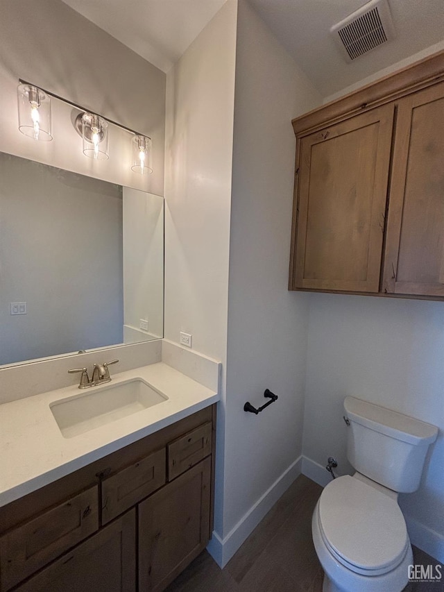 bathroom featuring visible vents, vanity, wood finished floors, toilet, and baseboards