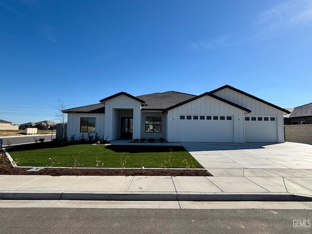 view of front facade featuring an attached garage, board and batten siding, concrete driveway, and a front yard