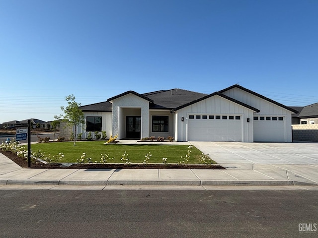 single story home with a front lawn, a garage, board and batten siding, concrete driveway, and a tiled roof