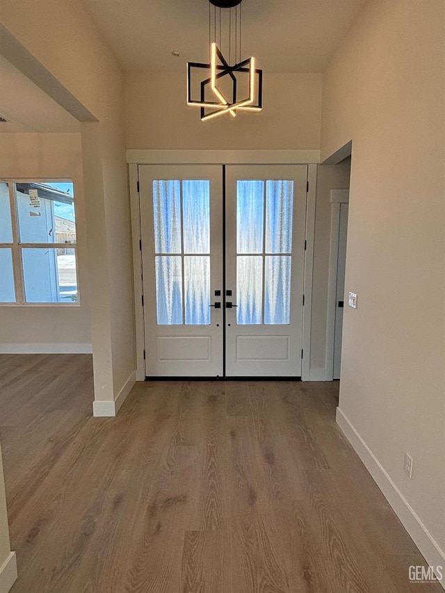 entryway featuring baseboards, wood finished floors, and french doors