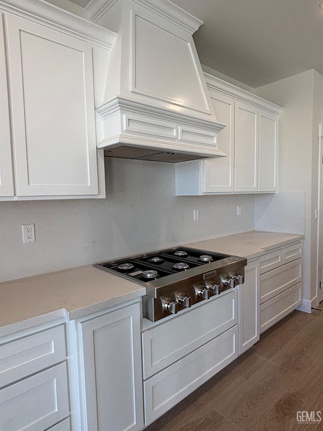 kitchen featuring white cabinets, dark wood finished floors, custom range hood, light countertops, and stainless steel gas stovetop