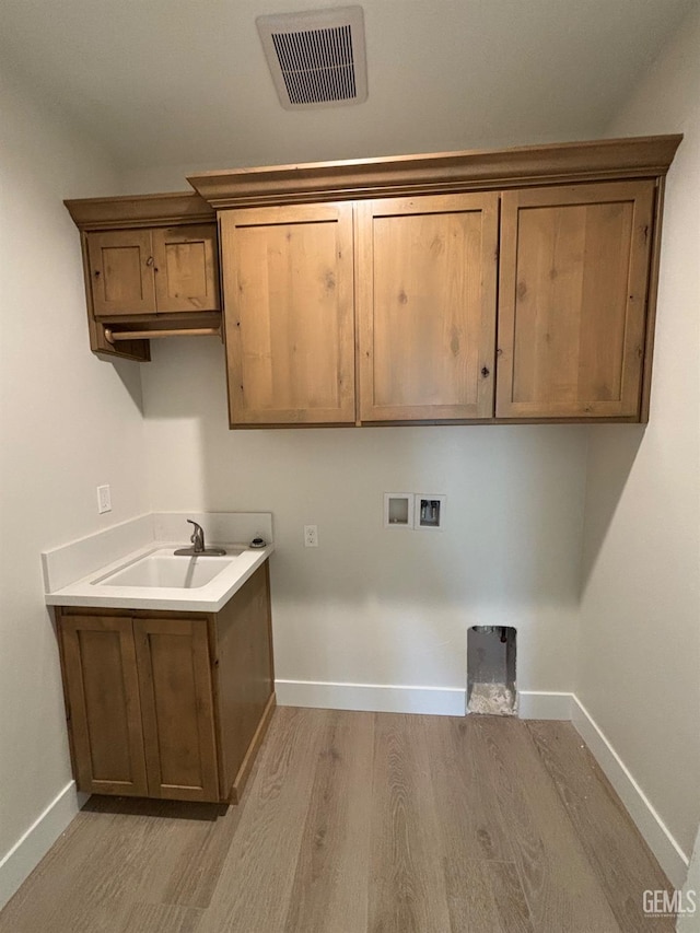 washroom featuring hookup for a washing machine, cabinet space, visible vents, a sink, and baseboards