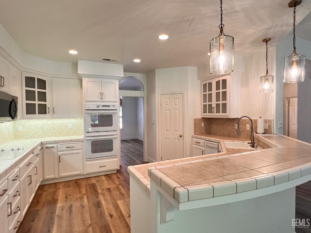 4812 Prairie Meadows Way, Bakersfield, CA 93312 - kitchen with double oven, light wood-type flooring, white cabinets, recessed lighting, and a peninsula