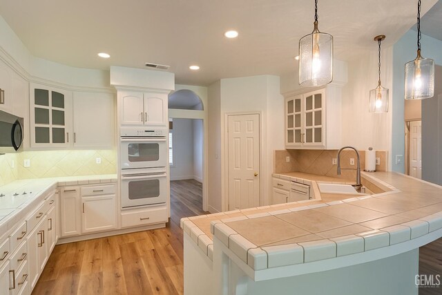 4812 Prairie Meadows Way, Bakersfield, CA 93312 - kitchen featuring double oven, light wood finished floors, stainless steel microwave, white cabinetry, and recessed lighting