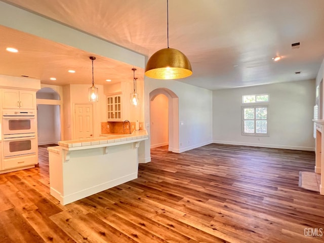 4812 Prairie Meadows Way, Bakersfield, CA 93312 - kitchen with arched walkways, tile countertops, open floor plan, light wood-style floors, and recessed lighting