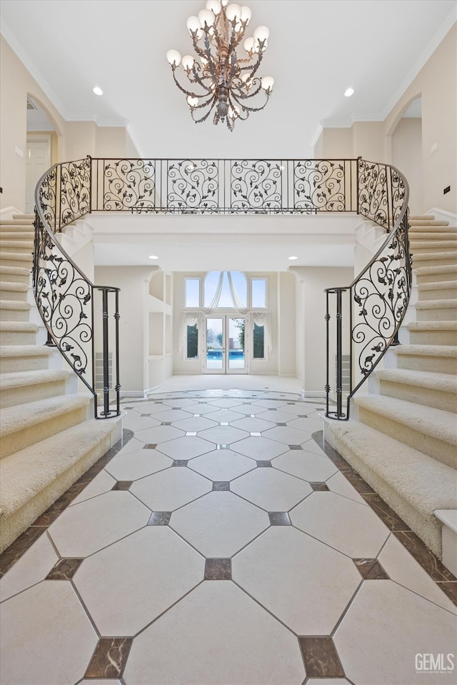 foyer entrance with a chandelier, french doors, ornamental molding, and a high ceiling