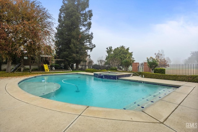 view of pool featuring an in ground hot tub and a playground