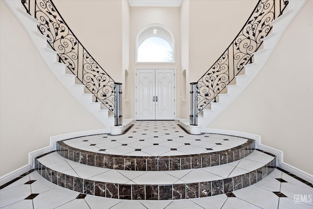 foyer entrance with tile patterned floors and a towering ceiling