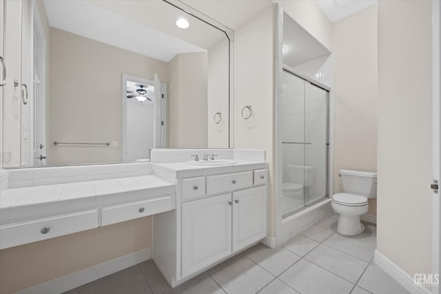 bathroom featuring ceiling fan, tile patterned flooring, toilet, vanity, and a shower with shower door