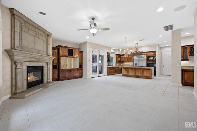 unfurnished living room with a fireplace, light tile patterned floors, and ceiling fan with notable chandelier