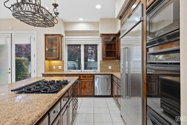 kitchen featuring light stone countertops, sink, black appliances, pendant lighting, and light tile patterned floors