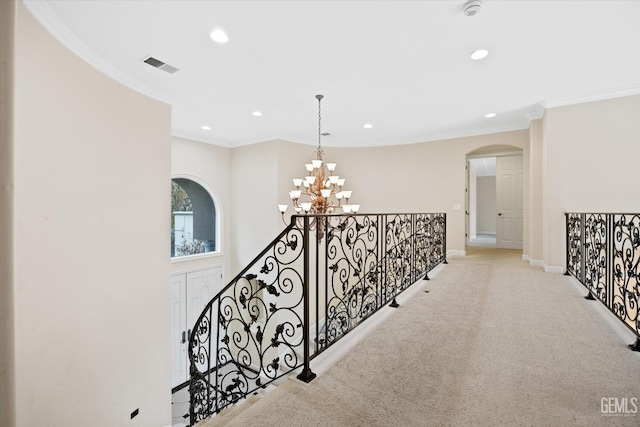 hall featuring a notable chandelier, crown molding, and light carpet