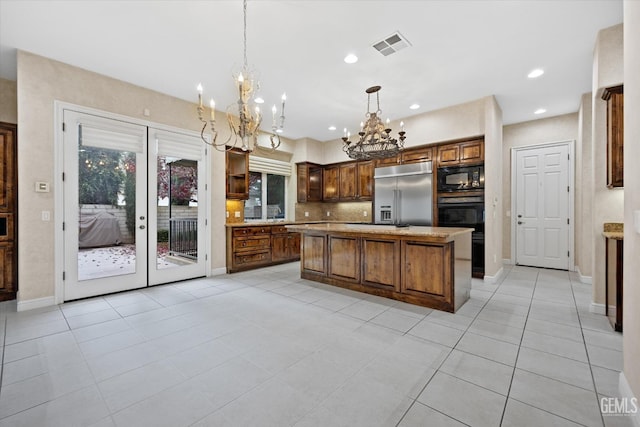 kitchen with a kitchen island, backsplash, decorative light fixtures, light tile patterned flooring, and black appliances