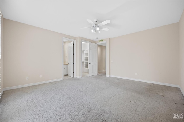 unfurnished bedroom featuring a walk in closet, ceiling fan, connected bathroom, light colored carpet, and a closet